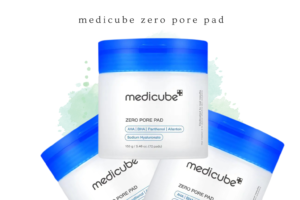 Three Medicube Zero Pore Pads with white containers and blue lids, showing AHA, BHA, Panthenol, Allantoin, and Sodium Hyaluronate, on a white background with light green and teal watercolor accents.